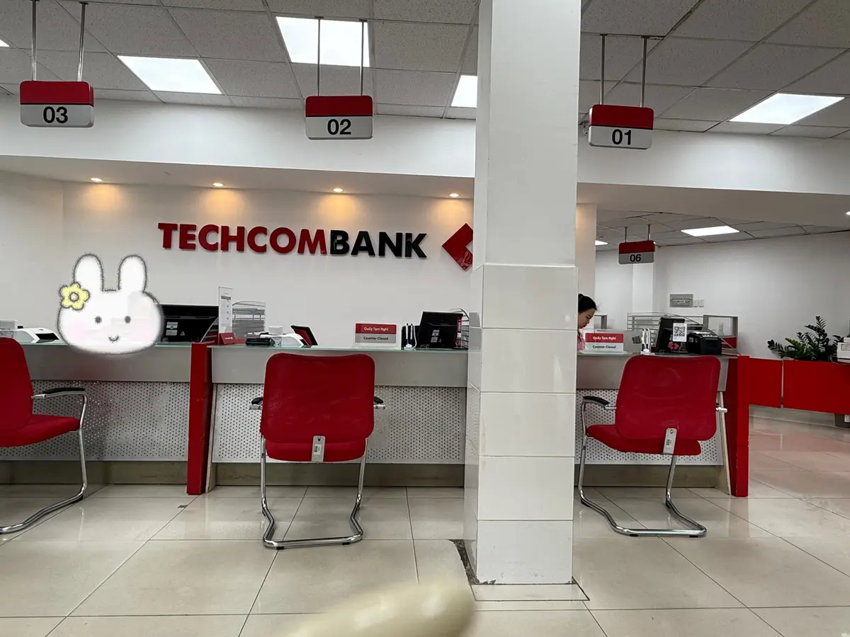 Teller counters with red chairs and numbered signs at a Techcombank branch.