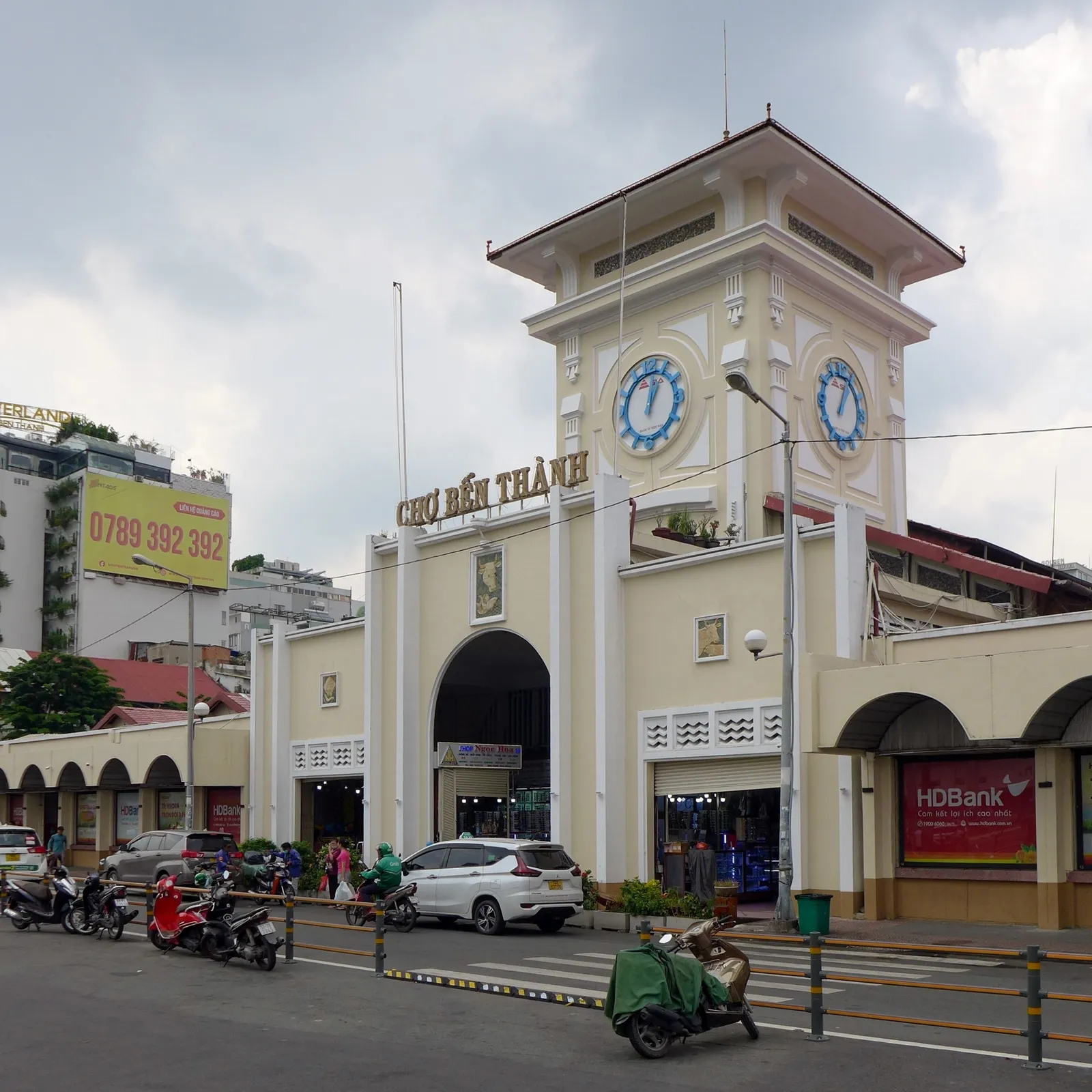 Market entrance with a clock tower and a Cho Ben Thanh sign above a street with parked motorbikes