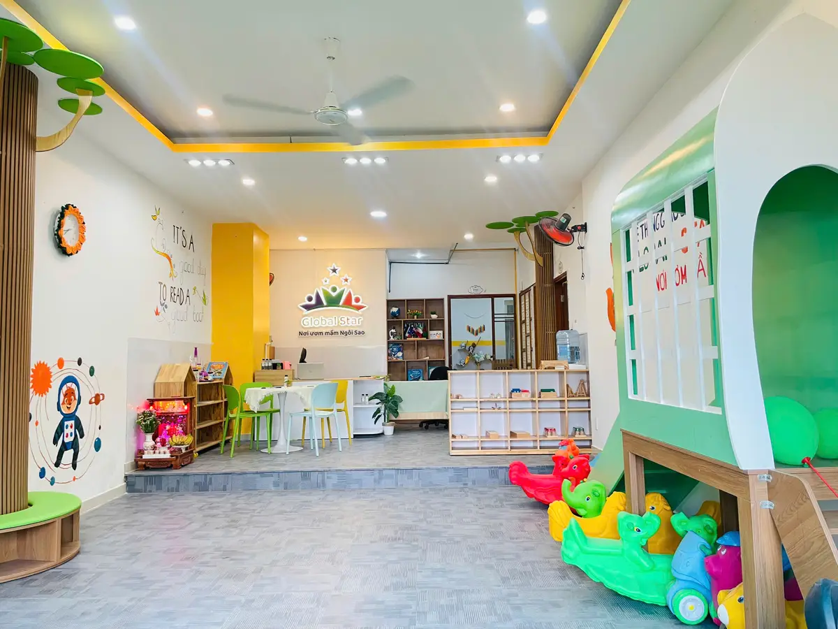 Bright reception area with a wooden play house, a green slide and shelves