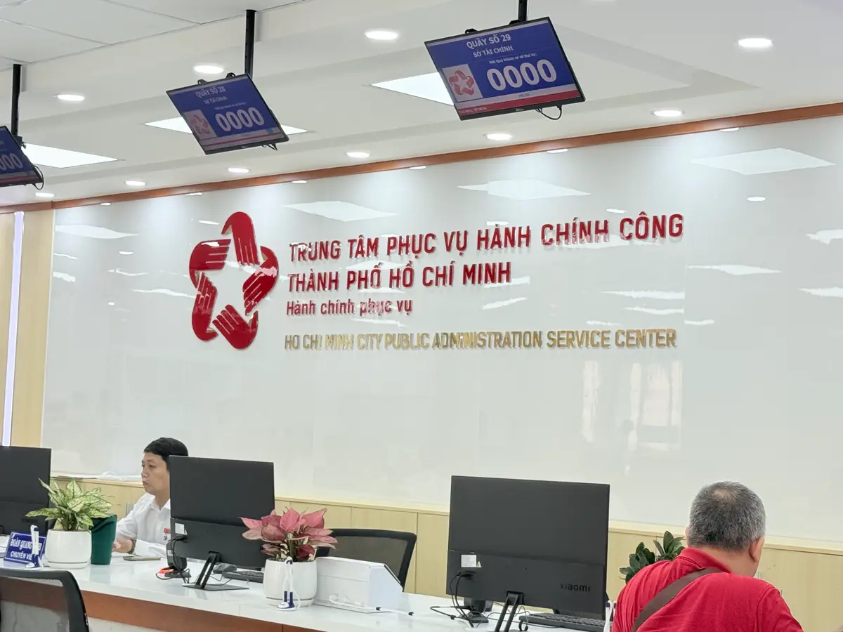 Service counters inside a public office, with a red logo sign on the wall behind them and staff at computers.