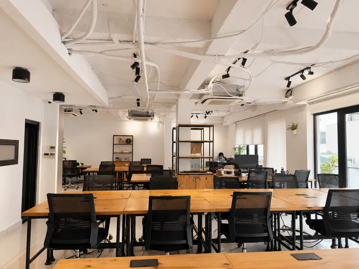 Bright open room with long desks and black mesh office chairs
