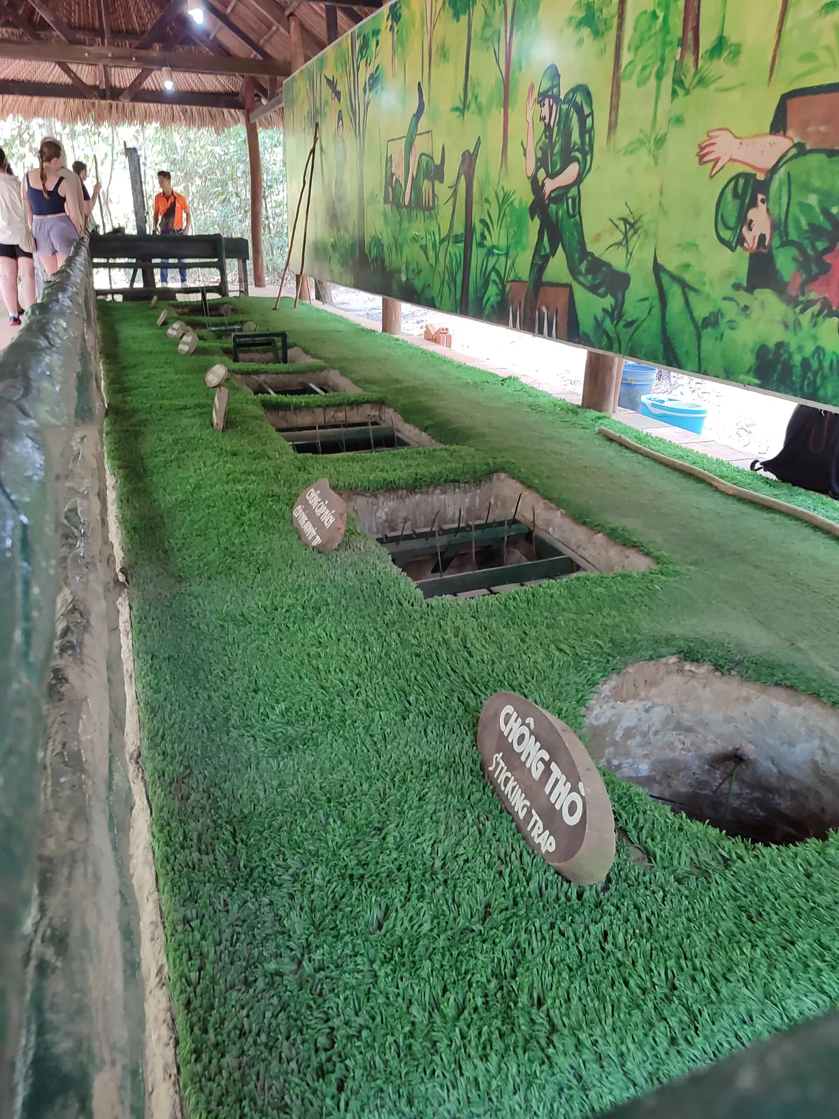 Row of small tunnel entrance holes in a grass-covered display beside a wooden sign