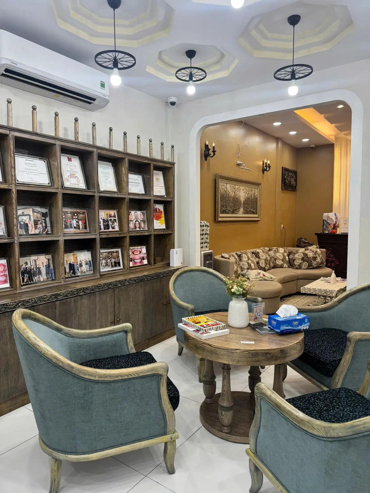 Seating corner with teal armchairs, a low table and shelves of framed certificates.