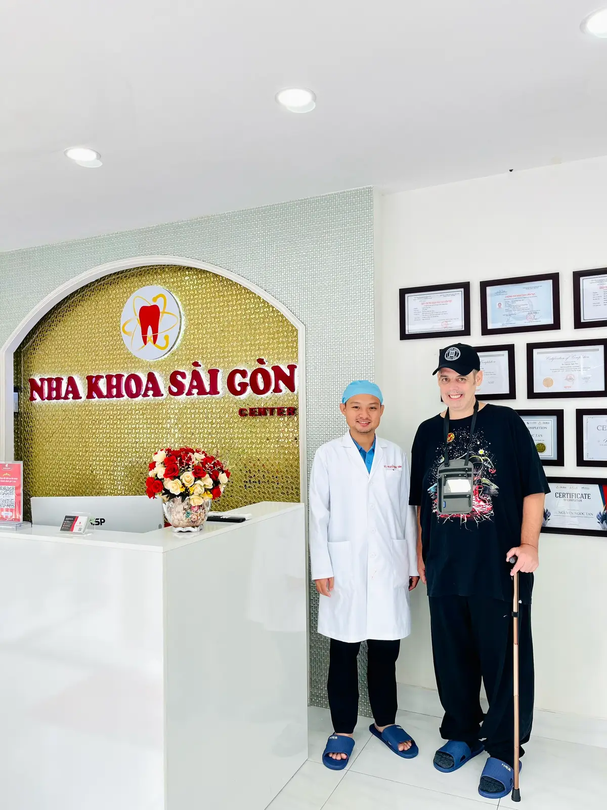 Gold wall sign with a tooth logo above a white reception desk and framed certificates.
