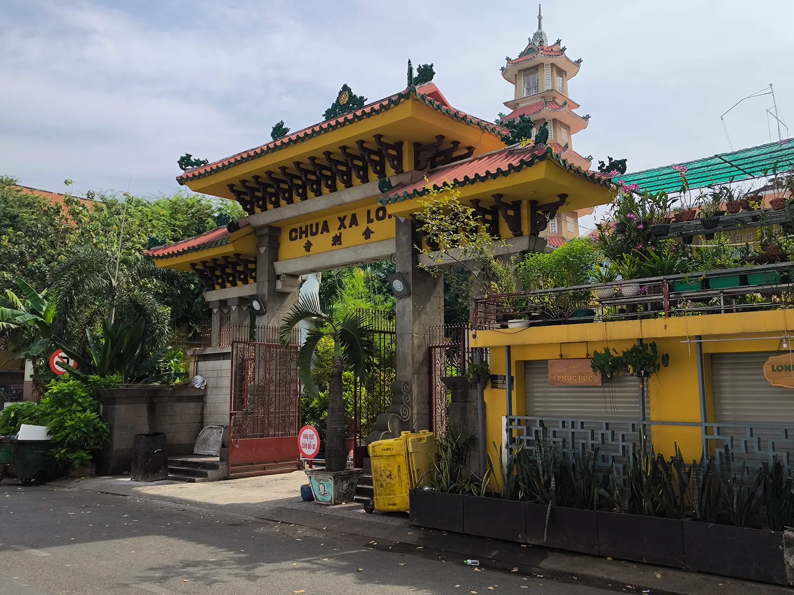 Yellow-tiled pagoda gate with a tower behind it at the end of a quiet street