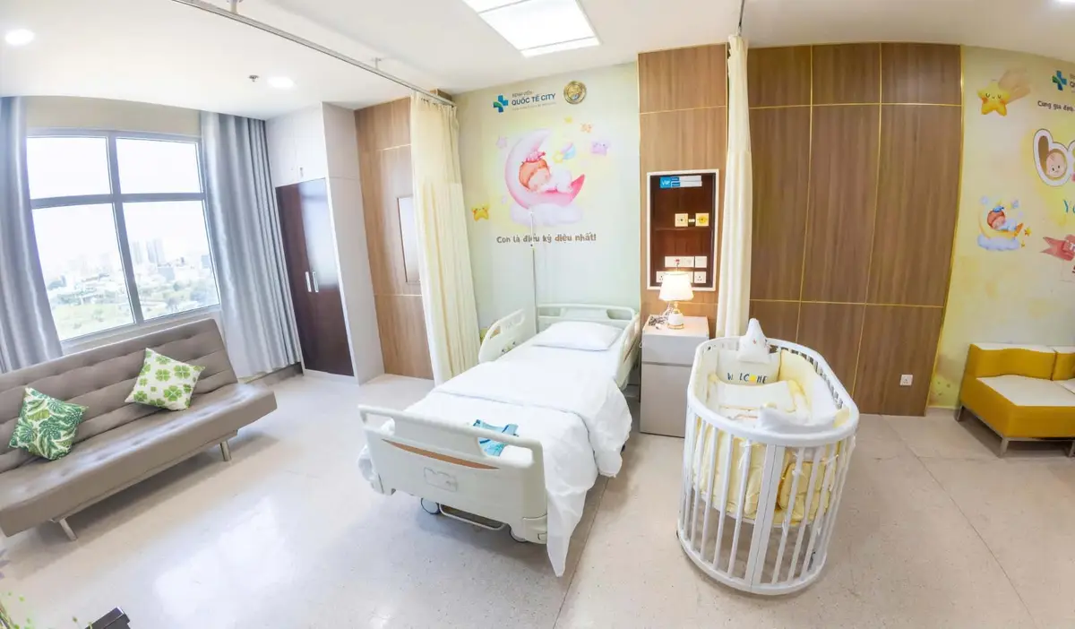Single maternity room at City International Hospital with a bed, sofa and baby crib.