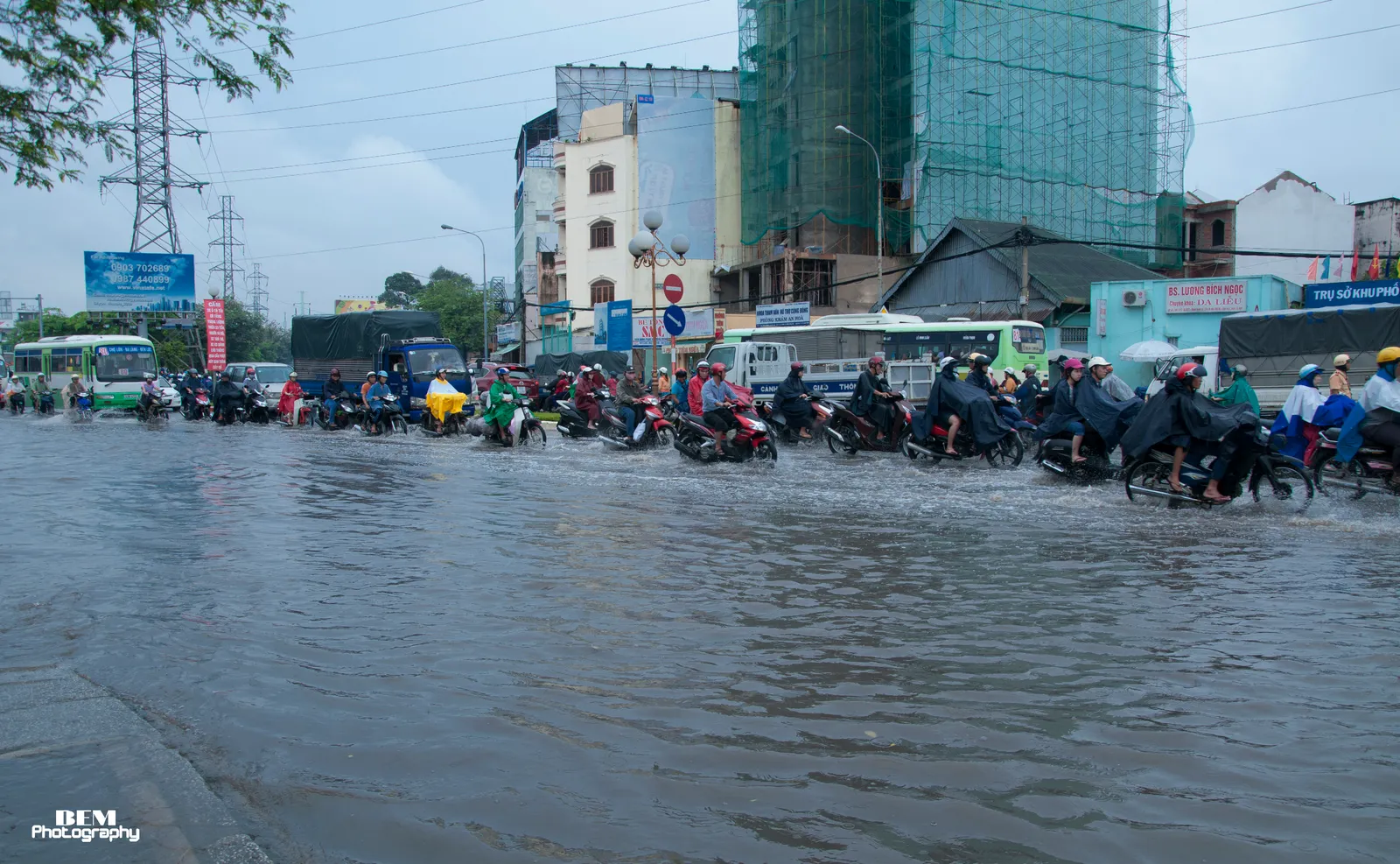 Crowd of motorbikes riding through water on a wide city road