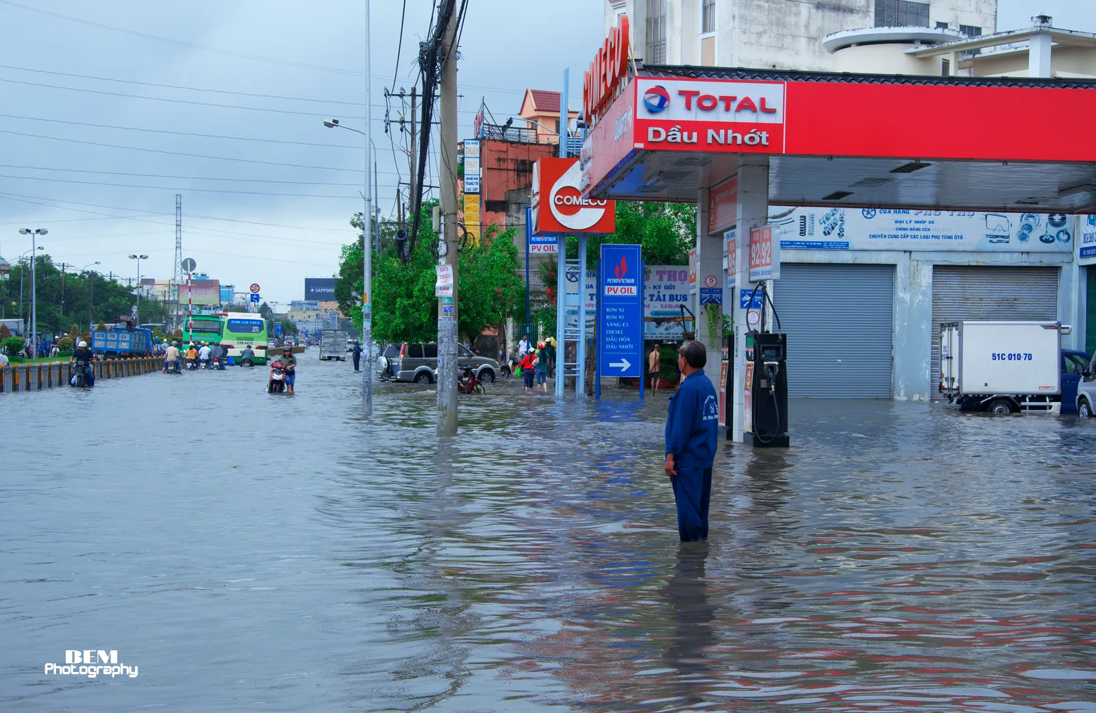 Flooded road beside a fuel station with a man standing in the water