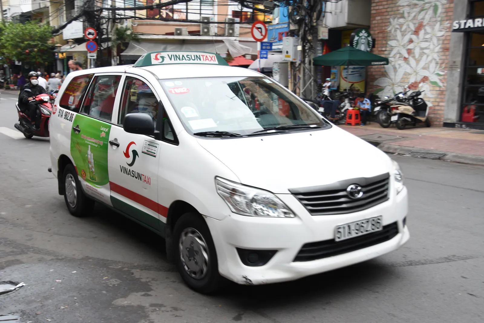 White minivan taxi with a green and red stripe on a city street