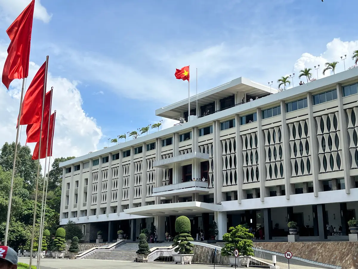 Palace front with stone screens on the upper floor and red flags flying beside the entrance steps