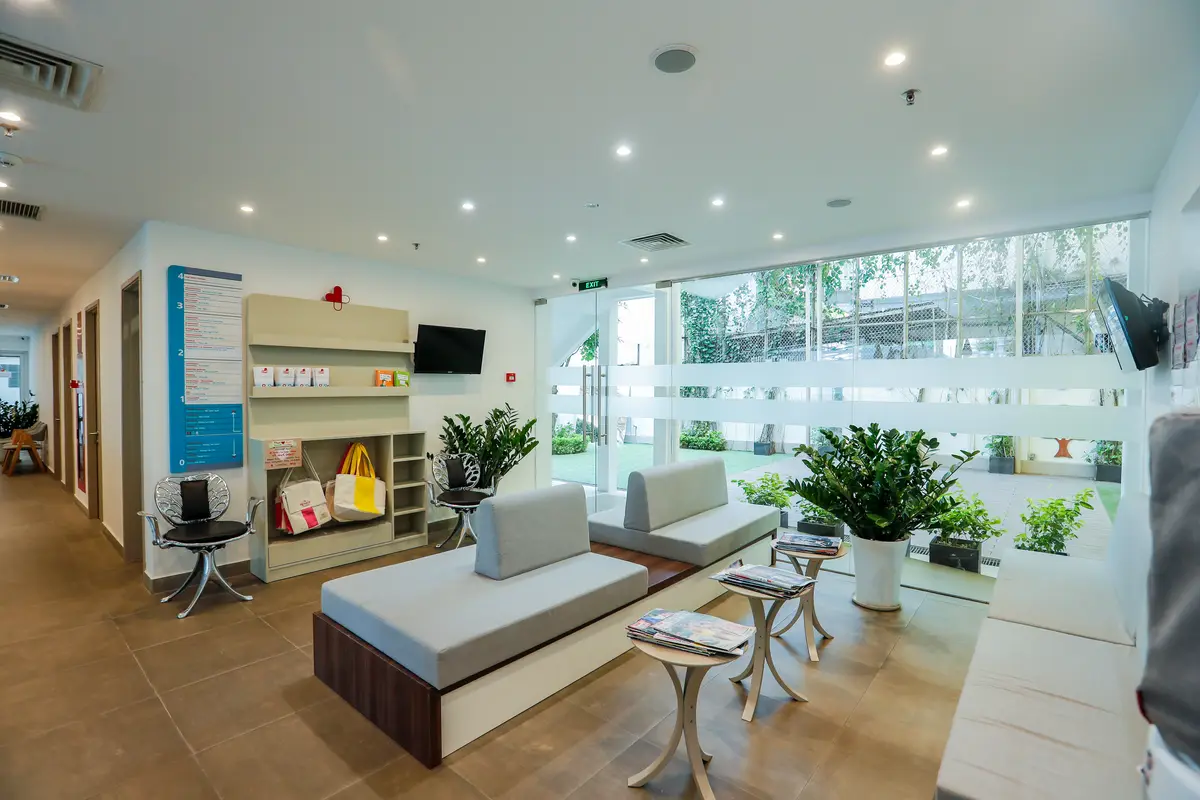 Bright waiting room with grey benches, plants and glass walls at the CMI clinic.