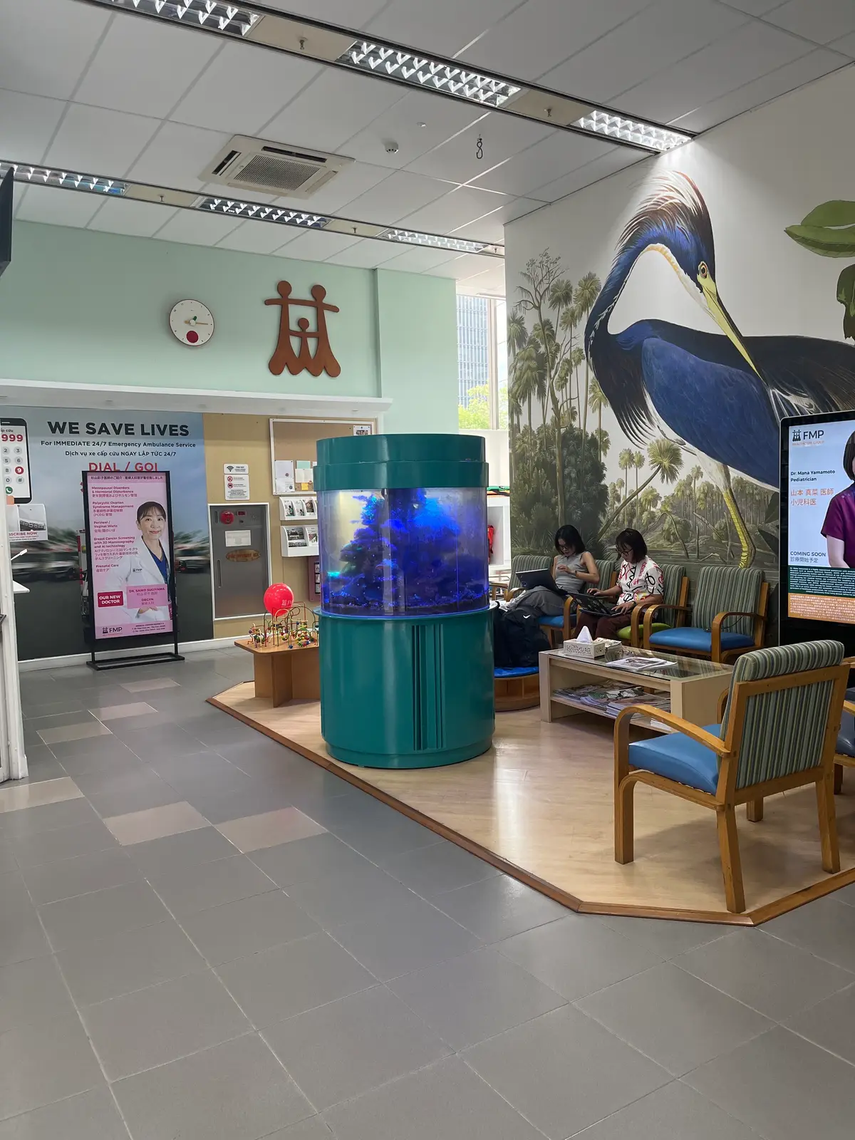 Reception waiting area at Family Medical Practice with armchairs, an aquarium and a wall mural.