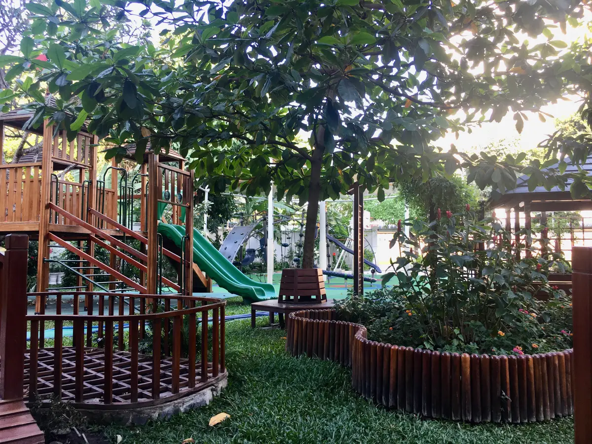 Wooden playground with a green slide among trees