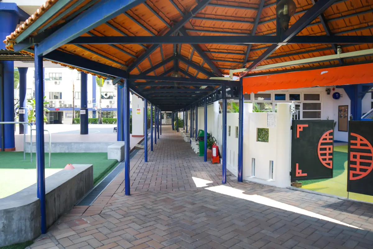 Covered brick walkway with blue posts beside a green courtyard