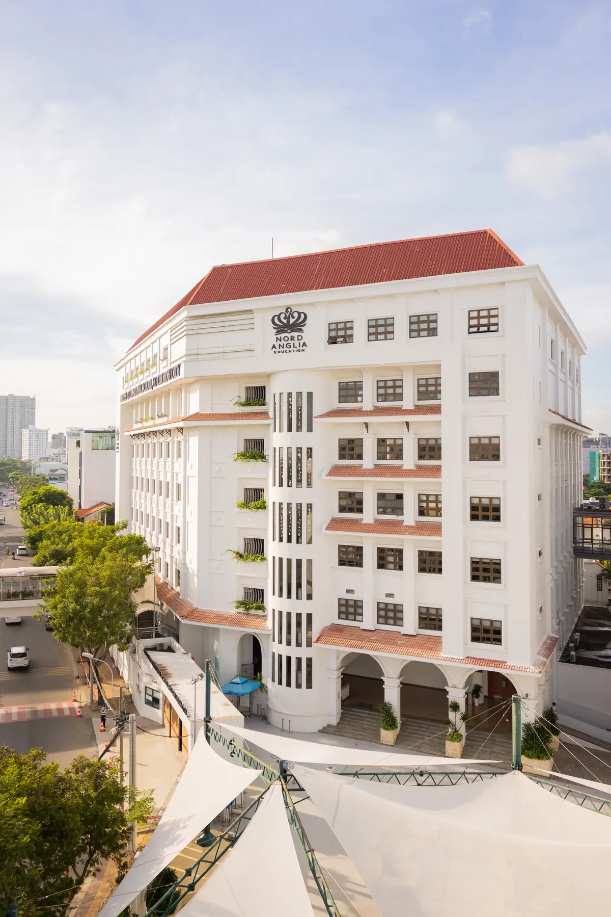 White multi-storey school building with red trim beside a street