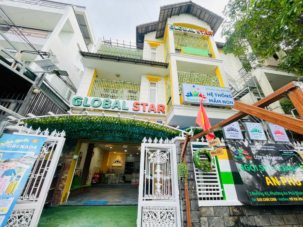 Multi-storey yellow and white building with a green school name sign above a white gate