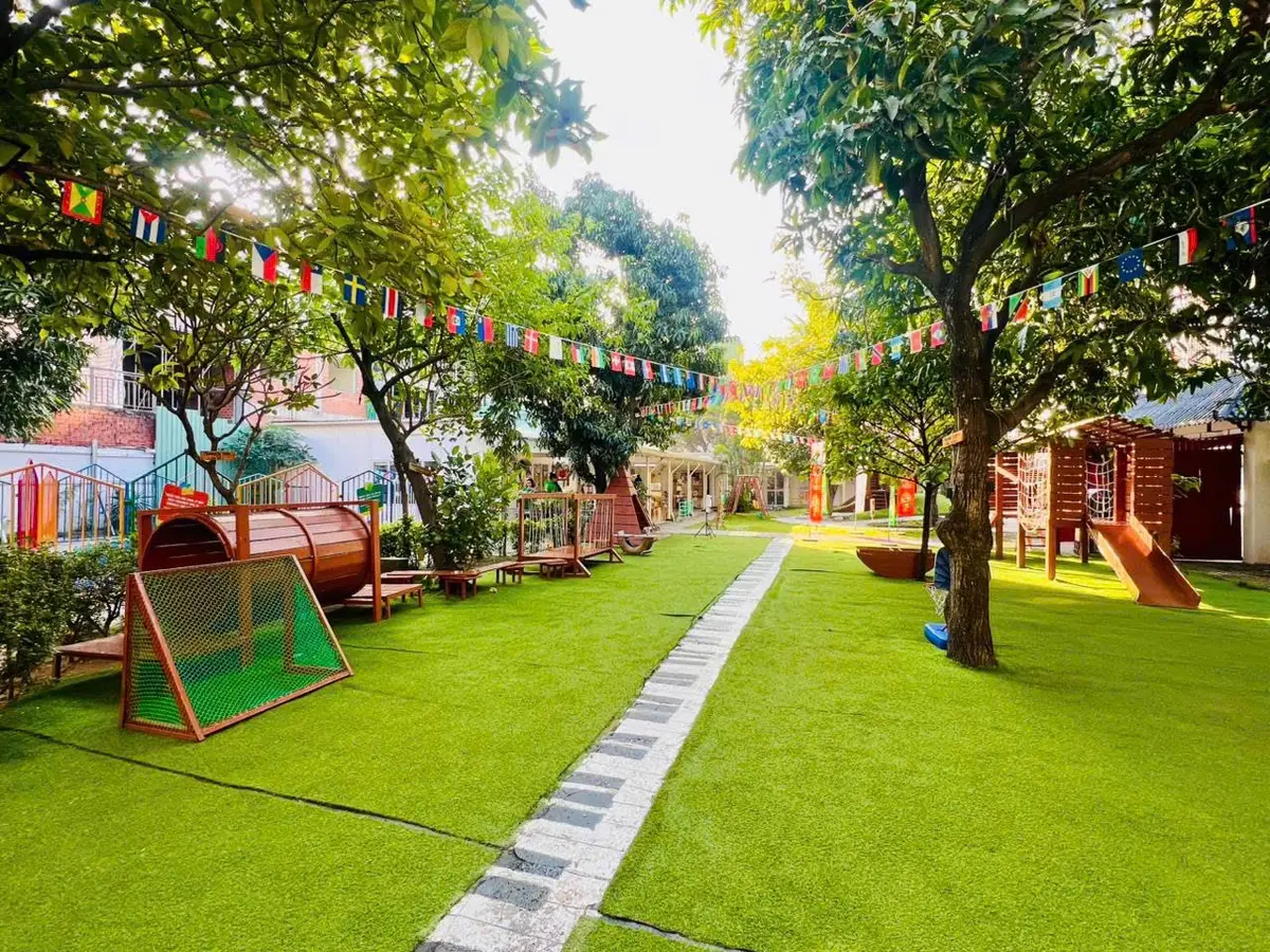 Grass lawn with a stone path, wooden play frames and shade trees
