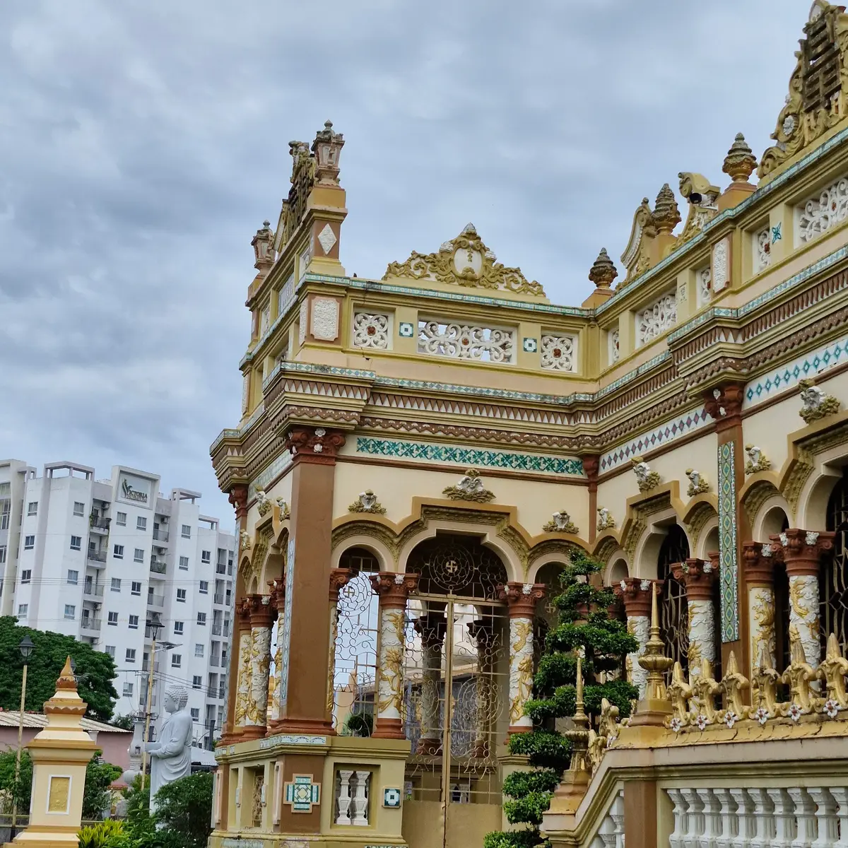 Ornate pagoda facade with carved balconies and columns beside a modern apartment block