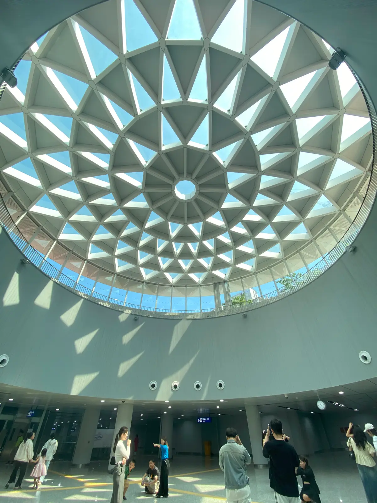 Looking up at a round skylight with a star-shaped glass pattern above a station concourse
