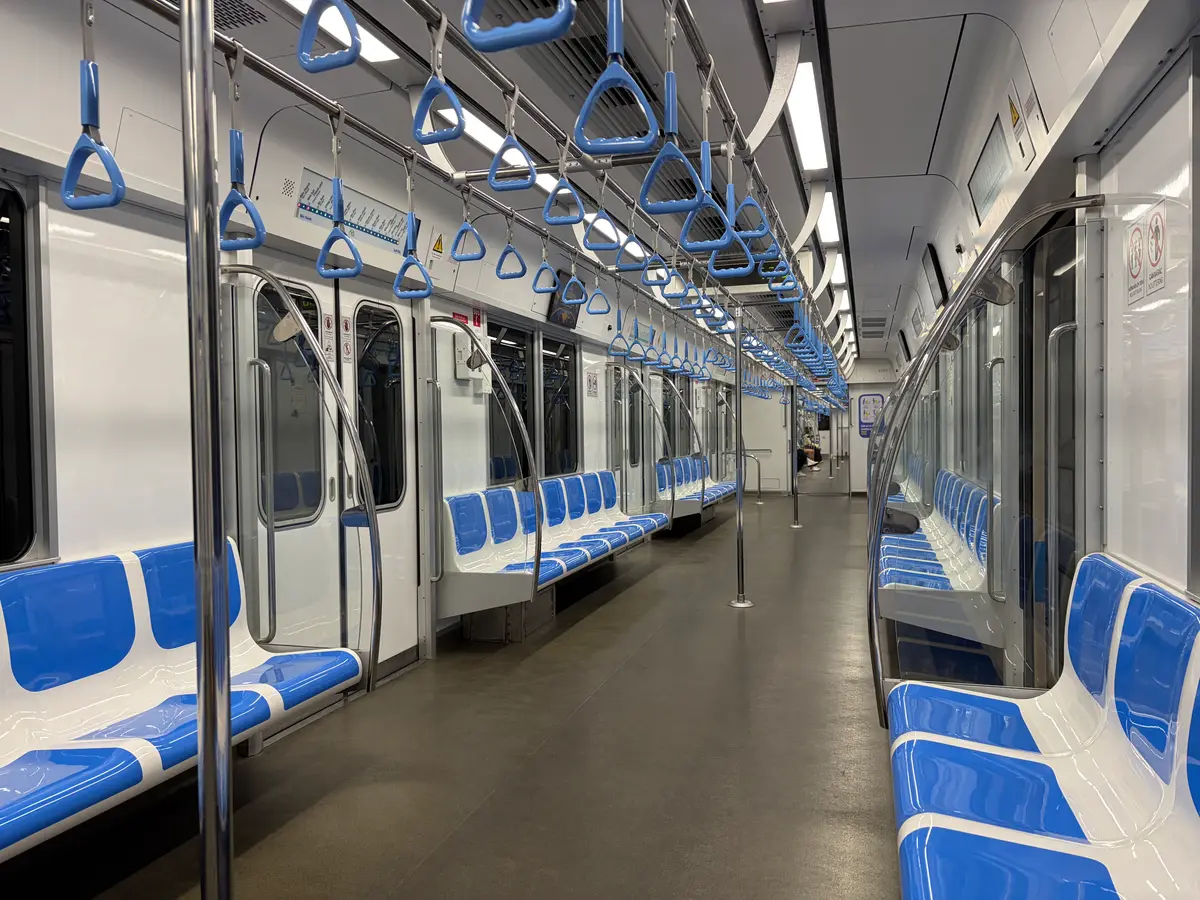 Inside a metro carriage with blue seats, hand straps and wide doors