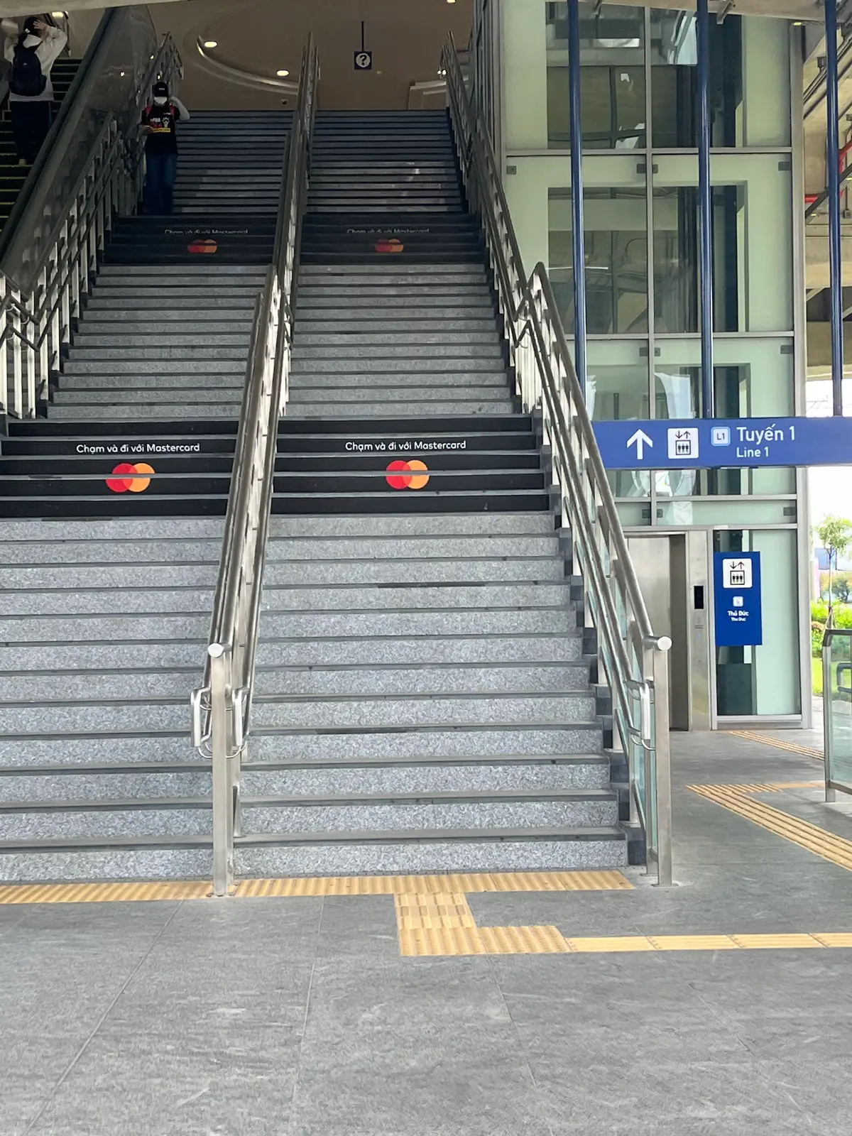 Station stairs with contactless card symbols on the steps and a lift sign beside them