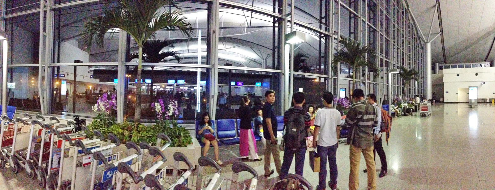 Airport hall with luggage trolleys and travellers waiting