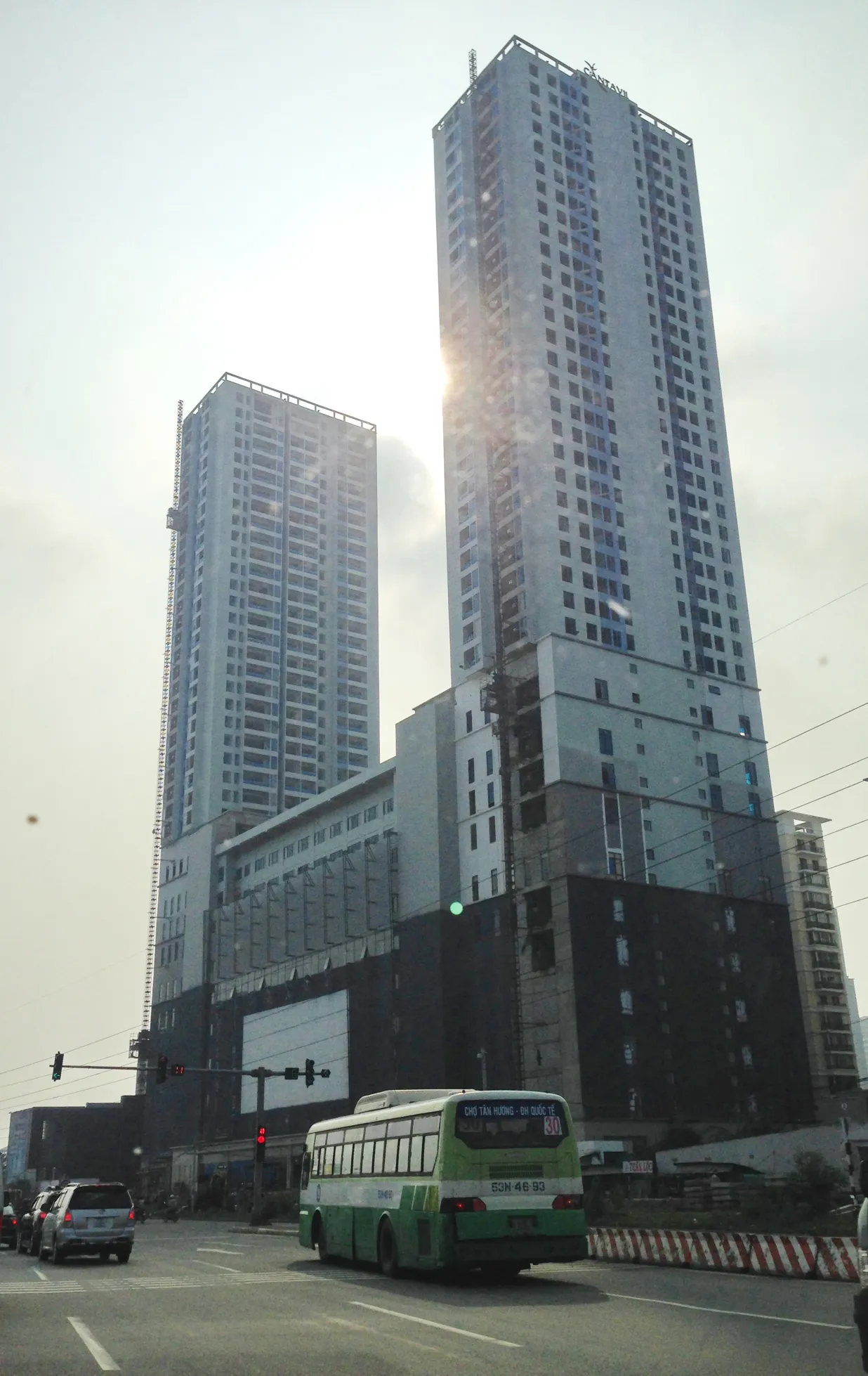 Tall apartment towers with a green city bus passing on the street below