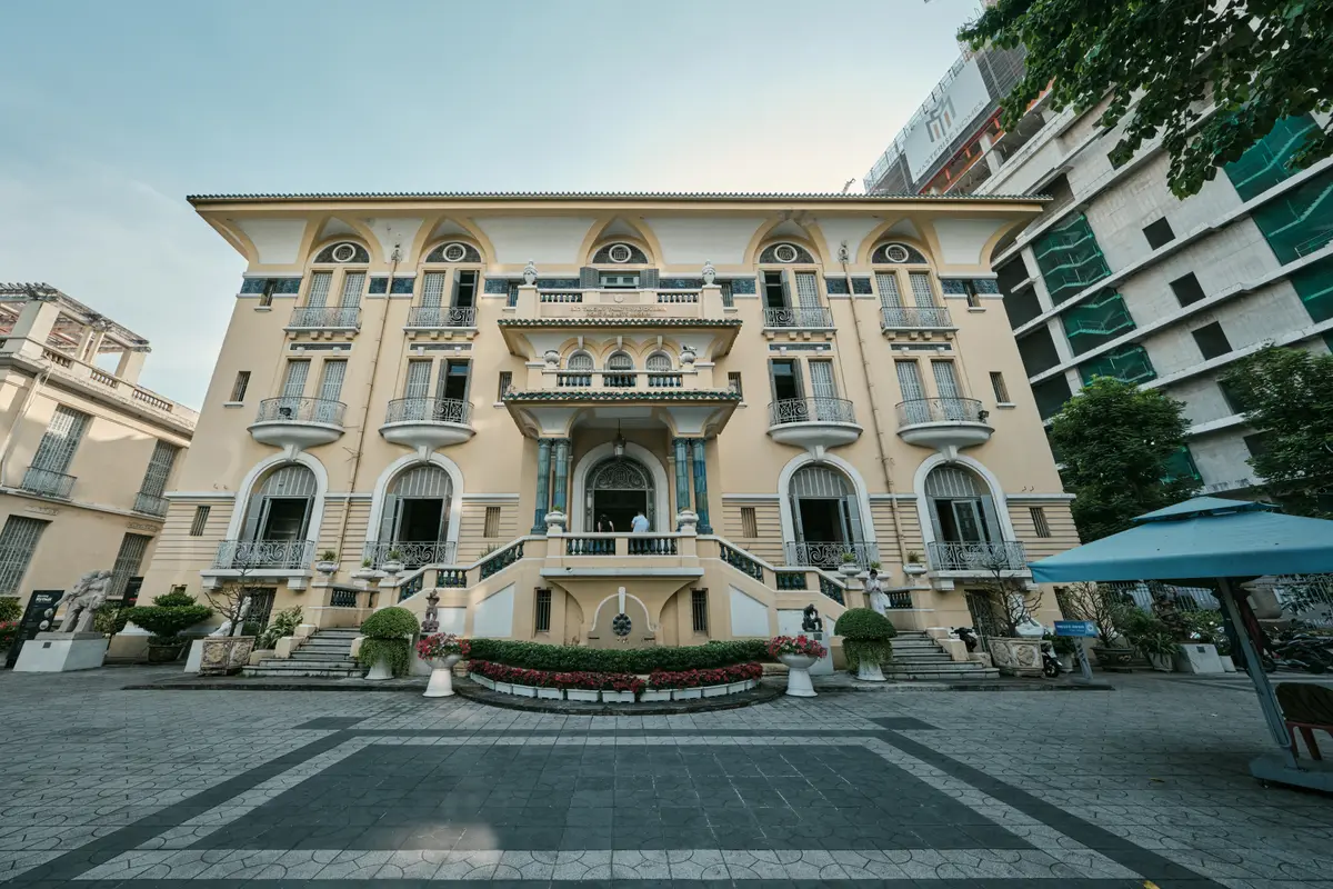 Cream-coloured colonial mansion with arched windows and balconies seen across a paved courtyard