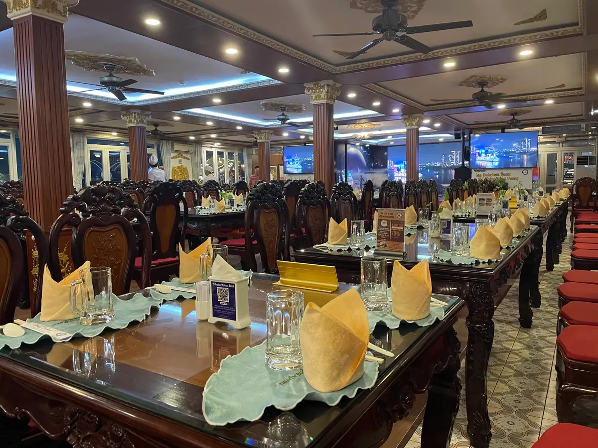 Dining room with long tables, folded yellow napkins and wooden chairs