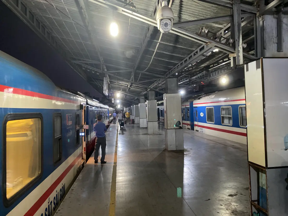 Blue and white carriages standing at a lit platform under a long roof