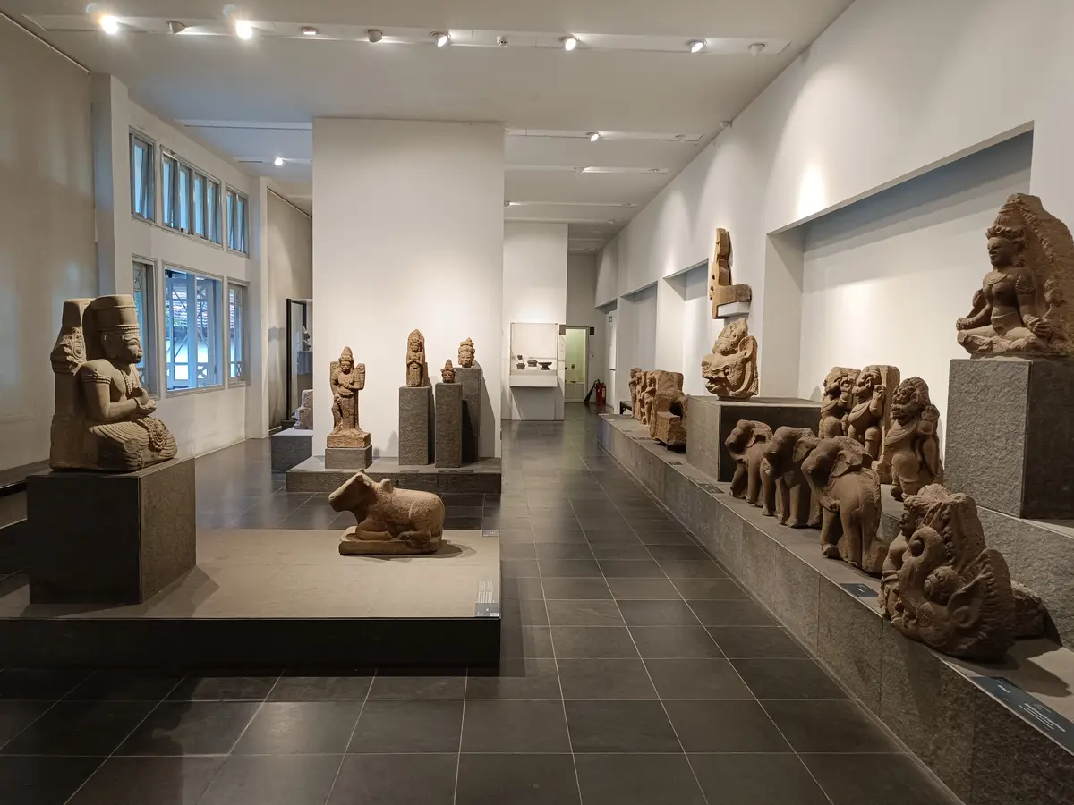 Bright gallery with carved sandstone sculptures on stands and low plinths along the walls