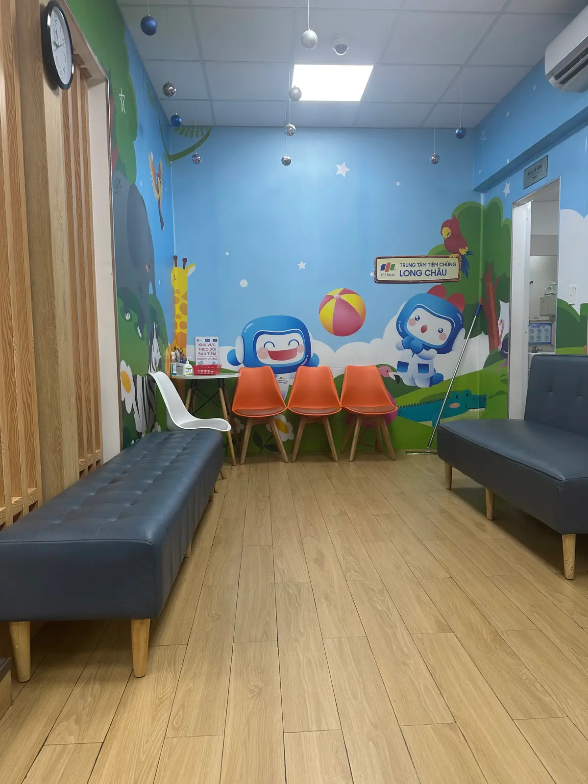 Waiting area with grey benches, orange chairs and a wall painted with cartoon characters at a Long Chau site.