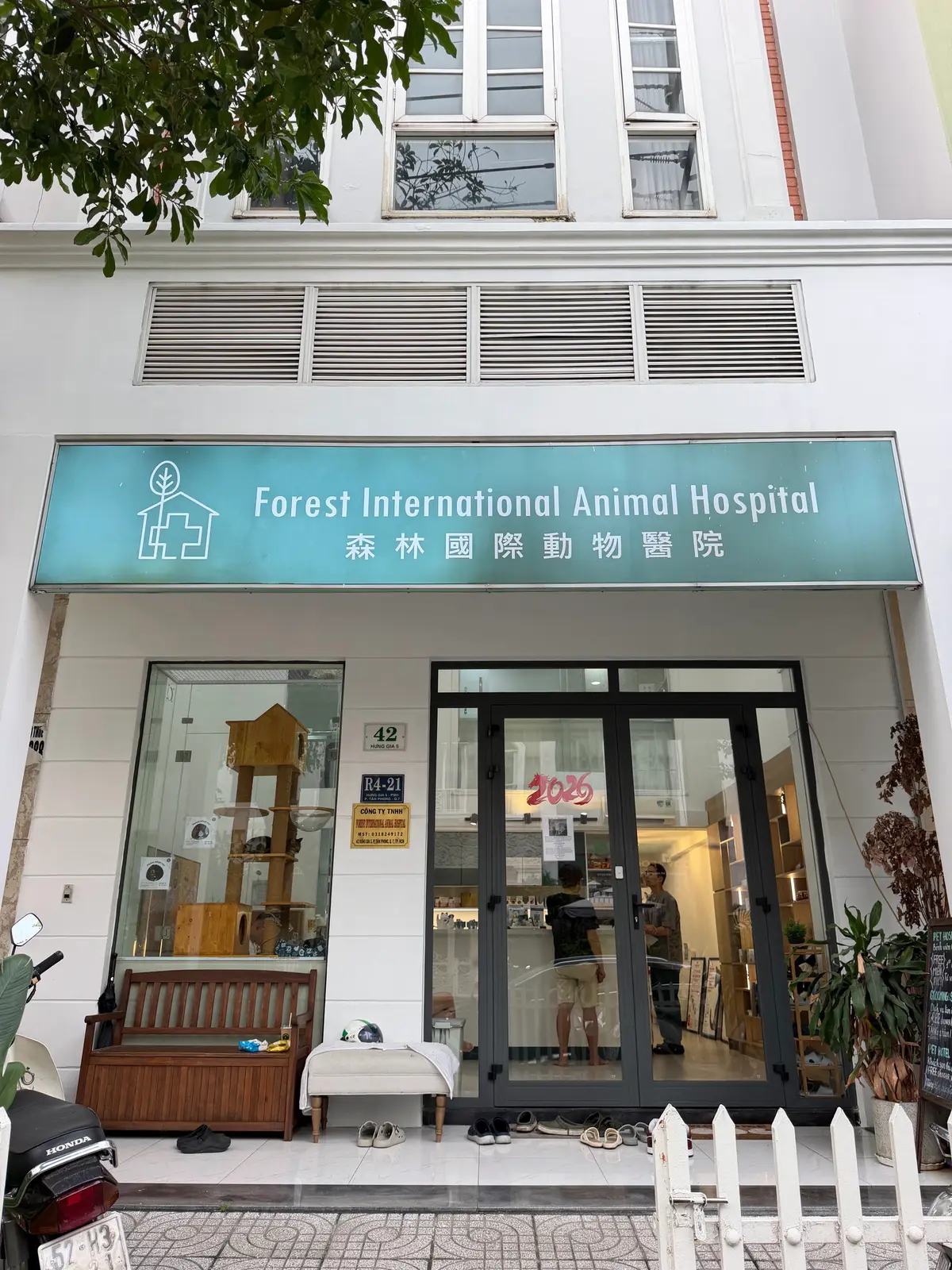 Shop front with a teal name sign above glass doors and a street number beside them