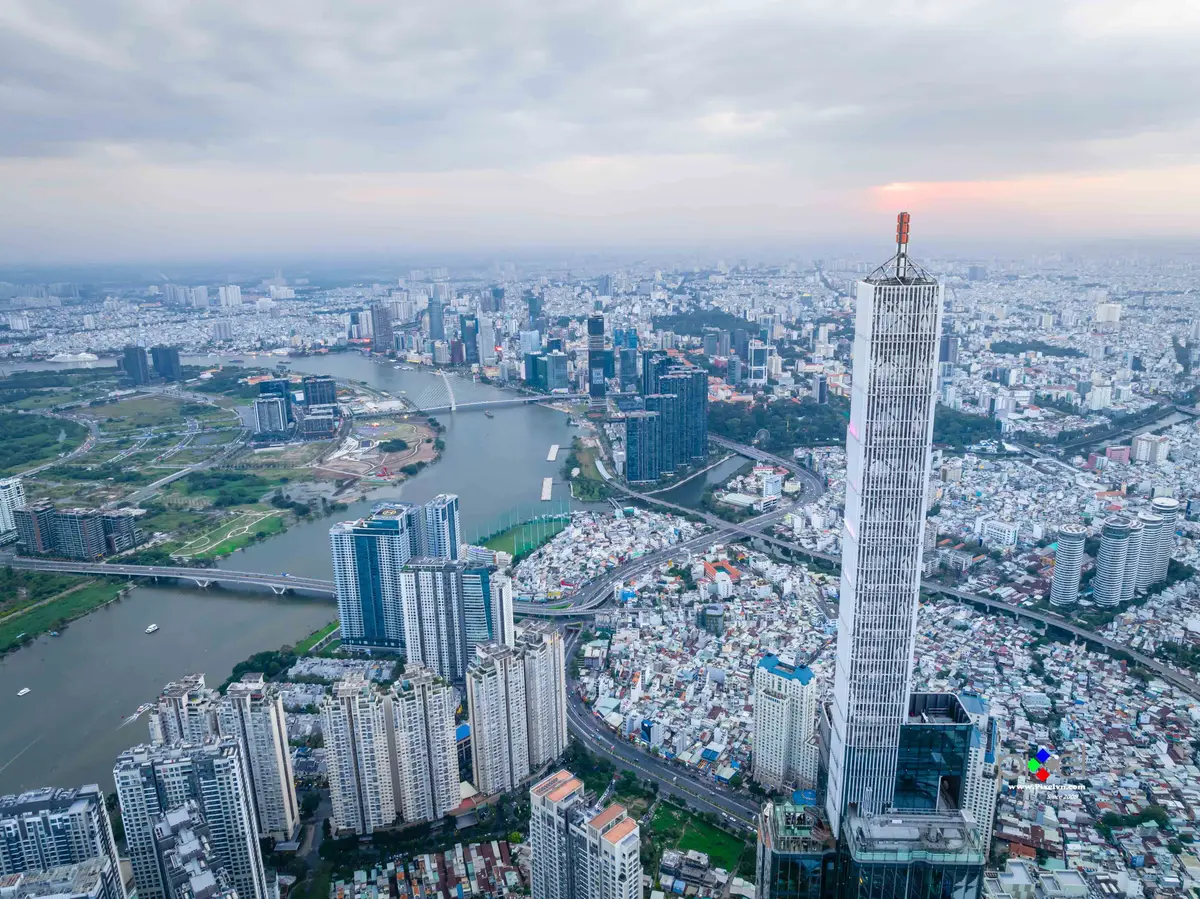 Aerial view of a tall tower beside a river bend with dense housing and green parks around it