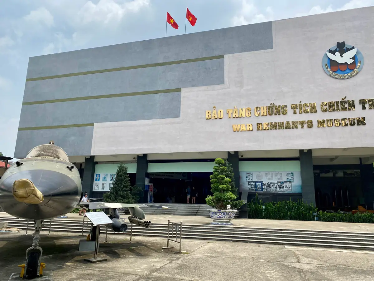 Grey museum building with a gold sign above the entrance and an aircraft nose in the foreground